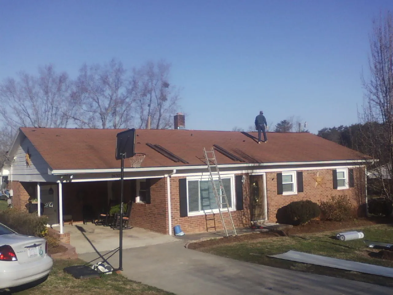 Roofer stripping a shingle roof on a brick ranch before metal panels in Wadsworth