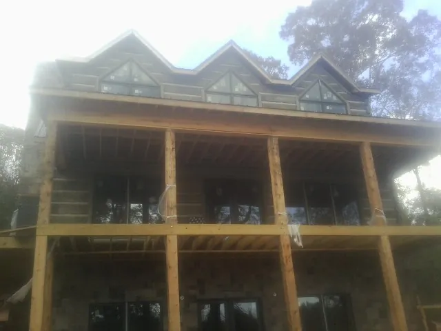 Dormers and porch framing on a large log home under construction — Roof Coating work by our crew in Wadsworth