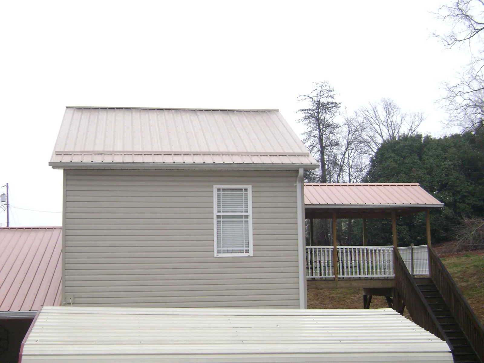 Tan metal roofs on a two story addition and attached porch, from a Roof Replacement job in Wadsworth